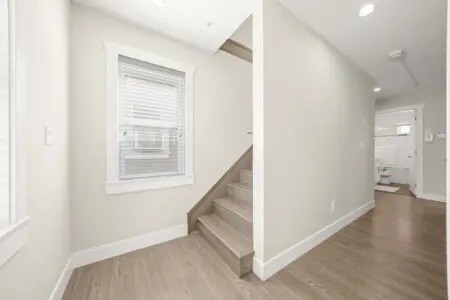A bright landing area leads to the staircase up to the third floor, where guests will find additional living space and comfort. Clean lines and natural light enhance the home’s open, welcoming feel.