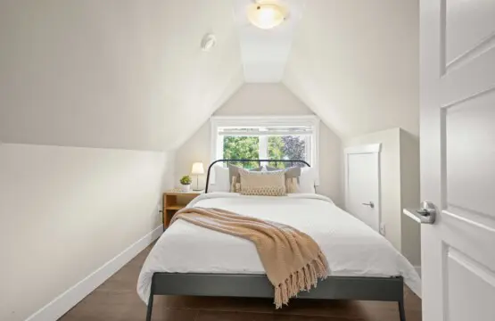 Tucked beneath charming vaulted ceilings, the third-floor bedroom offers a cozy and private retreat. A plush queen bed, soft lighting, and warm neutral tones create a peaceful atmosphere — perfect for unwinding after a day in the city.
