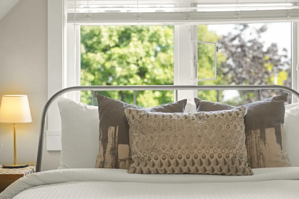 Soft textures and earthy tones bring tranquility to the third-floor bedroom. A plush queen bed framed by sunlit windows offers a peaceful spot to wake up to gentle morning light and views of the treetops — the perfect blend of comfort and calm.