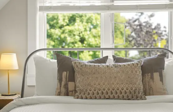 Soft textures and earthy tones bring tranquility to the third-floor bedroom. A plush queen bed framed by sunlit windows offers a peaceful spot to wake up to gentle morning light and views of the treetops — the perfect blend of comfort and calm.