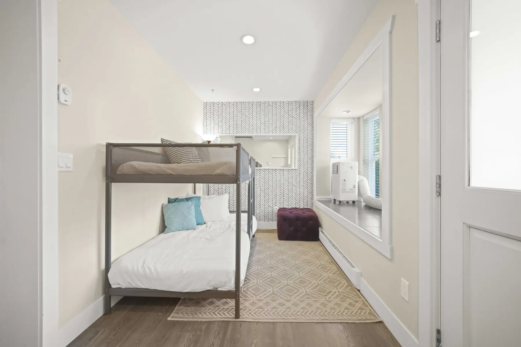 This inviting main-floor den features a cozy bunk bed setup for two, ideal for relaxing after a day in the city. With soft linens, warm lighting, and thoughtful modern details, it offers a peaceful retreat within the home.