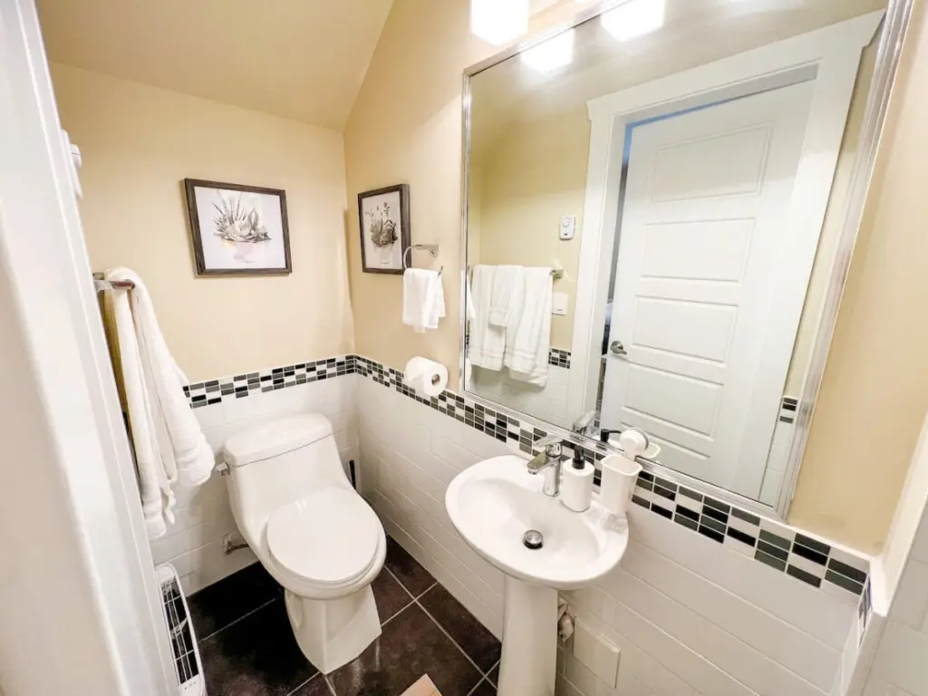 The main floor bathroom features a clean, modern design accented with soft lighting and tasteful decor. Thoughtfully stocked with essentials, it offers both comfort and convenience — a refreshing retreat within your furnished Vancouver suite.