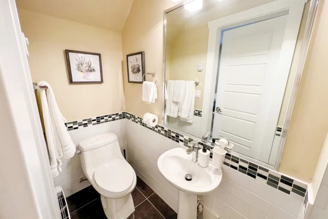 The main floor bathroom features a clean, modern design accented with soft lighting and tasteful decor. Thoughtfully stocked with essentials, it offers both comfort and convenience — a refreshing retreat within your furnished Vancouver suite.