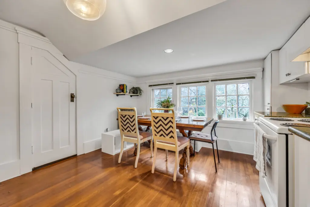 A charming dining area with a wooden table, stylish seating, and large windows that invite natural light, creating a bright and inviting space.