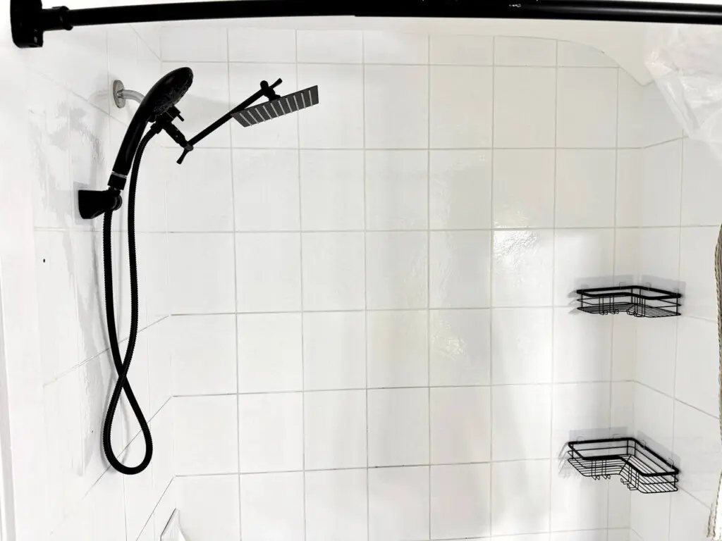 A sleek, modern shower setup featuring a black rainfall showerhead and convenient corner shelving for toiletries.