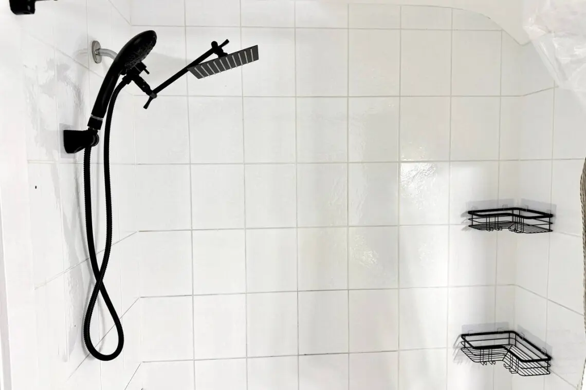 A sleek, modern shower setup featuring a black rainfall showerhead and convenient corner shelving for toiletries.