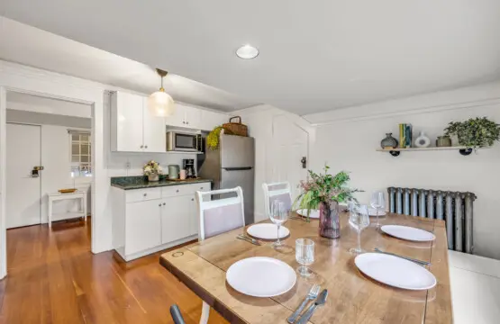 A cozy dining area with a charming wooden table, four seats, and a simple yet stylish design, featuring natural light and kitchen amenities for a relaxing meal experience.