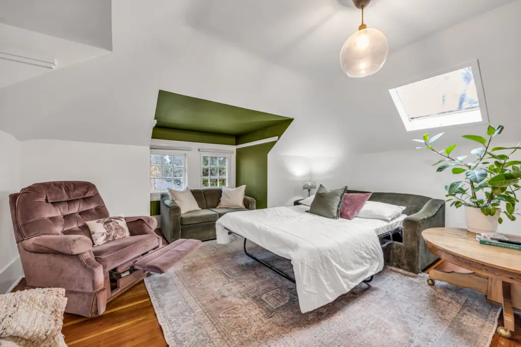 A cozy and inviting room featuring a plush recliner, comfortable seating, and a spacious bed, perfect for relaxation with natural light streaming in from the windows.