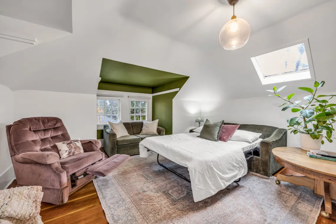 A cozy and inviting room featuring a plush recliner, comfortable seating, and a spacious bed, perfect for relaxation with natural light streaming in from the windows.