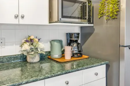 A cozy kitchen corner with a stylish kettle, coffee maker, and a vase of fresh flowers, perfect for morning routines.