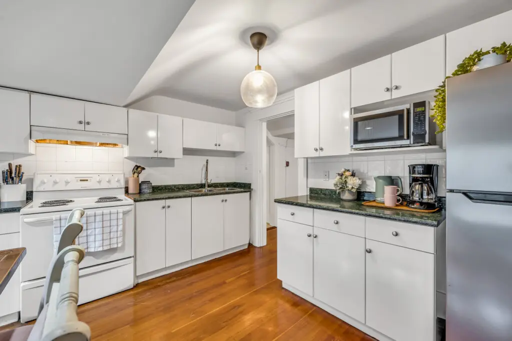 A well-lit kitchen with white cabinetry, granite countertops, and modern appliances, perfect for cooking and entertaining.