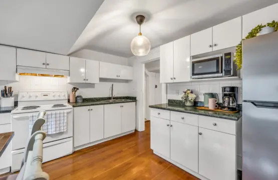 A well-lit kitchen with white cabinetry, granite countertops, and modern appliances, perfect for cooking and entertaining.