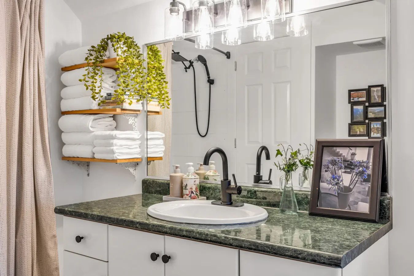 Bright, well-appointed bathroom with a spacious vanity, modern fixtures, plush towels, and open shelving for convenient storage.