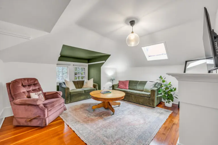 A bright and inviting loft-style living room with sloped ceilings and a cozy layout.