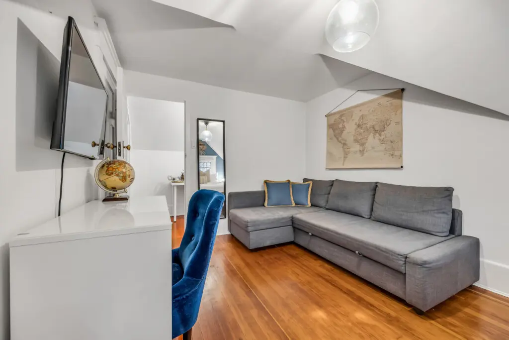 A cozy corner with a plush sectional sofa, wall-mounted TV, and a stylish world map print, perfect for relaxing or planning your next adventure.