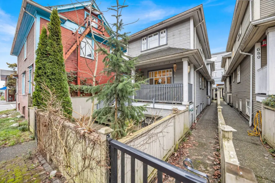 Charming exterior view showcasing a quaint house with a front porch, surrounded by greenery and an inviting walkway leading to the entrance.
