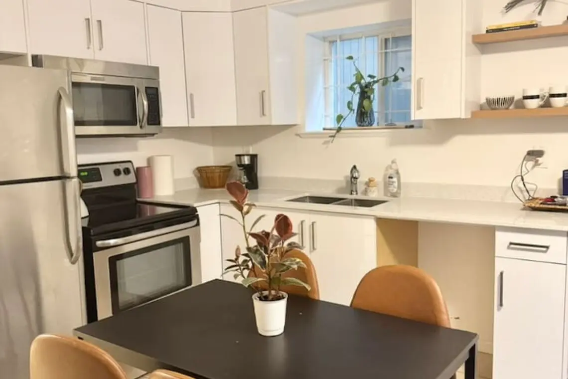 Modern kitchen with sleek appliances, open shelving, and a cozy dining nook, perfect for enjoying meals in a bright and airy space.