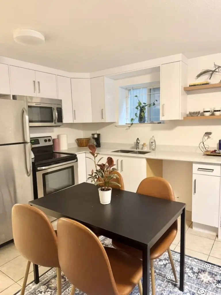 Modern kitchen with sleek appliances, open shelving, and a cozy dining nook, perfect for enjoying meals in a bright and airy space.