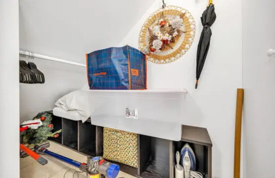 Organized storage space featuring shelves, a bag of items, and cleaning tools, perfect for keeping household essentials neatly tucked away.