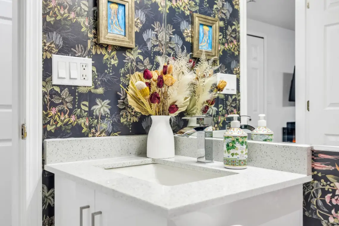 Charming bathroom with a stylish floral wallpaper, modern vanity, and decorative touches, creating a warm and inviting space.