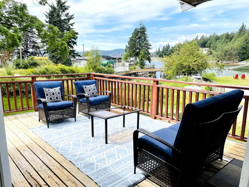 Relaxing outdoor seating area with cozy chairs, a glass table, and scenic views, perfect for enjoying a peaceful moment on the deck.