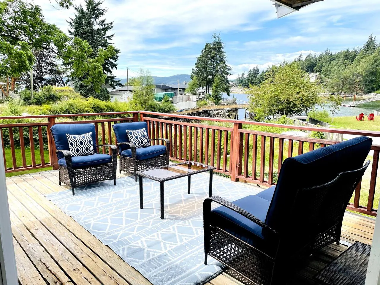 Relaxing outdoor seating area with cozy chairs, a glass table, and scenic views, perfect for enjoying a peaceful moment on the deck.