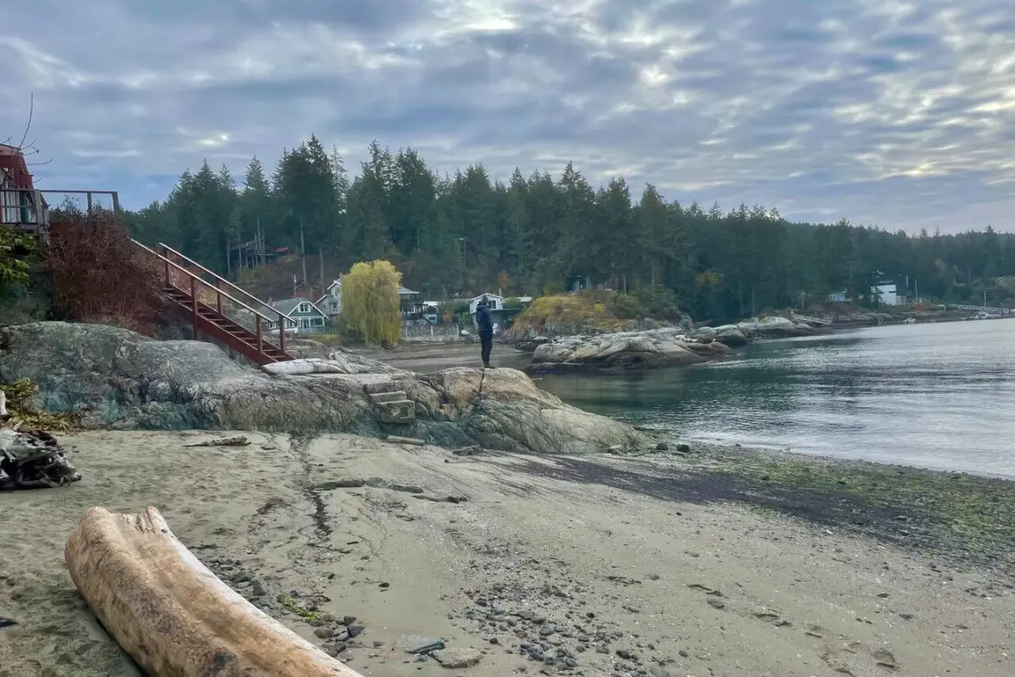 Peaceful beachside view with rocky shores, a wooden staircase, and a calm, scenic coastline, offering a tranquil escape by the water.