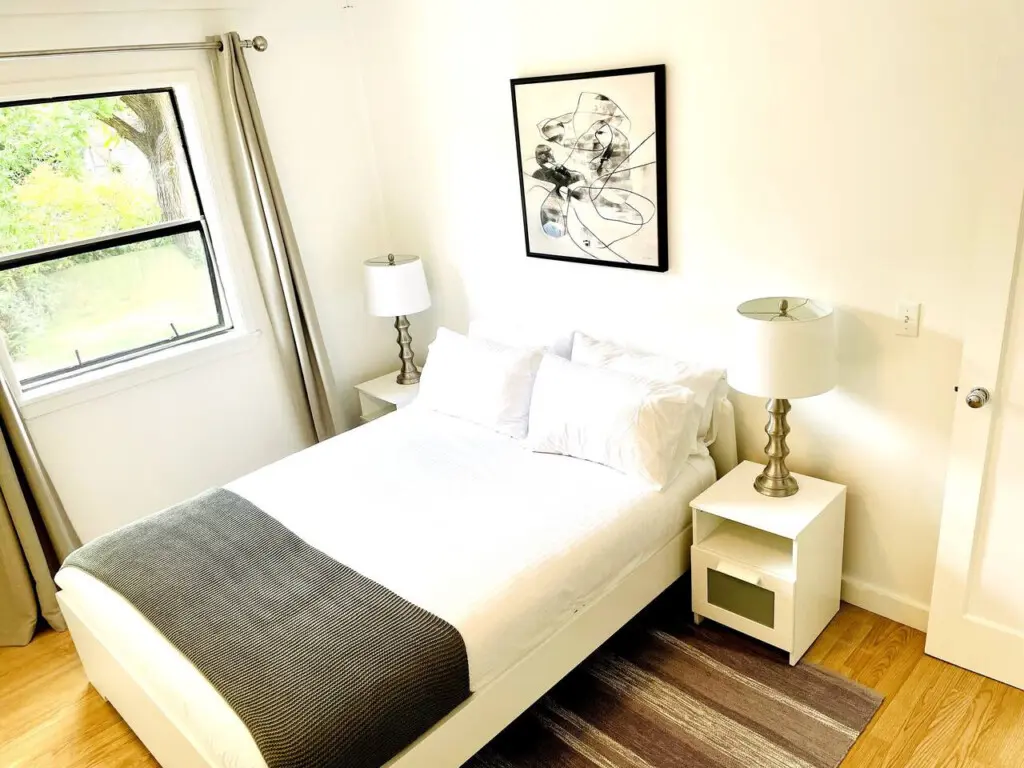 Cozy bedroom with a comfortable bed, modern side tables, and soft lighting, offering a peaceful retreat with natural light and stylish décor.