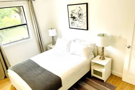 Cozy bedroom with a comfortable bed, modern side tables, and soft lighting, offering a peaceful retreat with natural light and stylish décor.