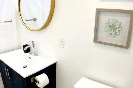 Modern bathroom featuring a stylish round mirror, sleek vanity, and minimalistic decor, creating a clean and inviting space.