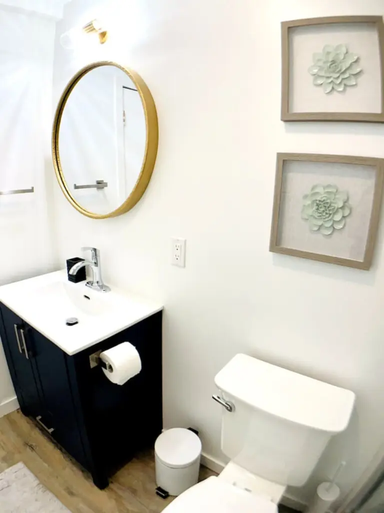 Modern bathroom featuring a stylish round mirror, sleek vanity, and minimalistic decor, creating a clean and inviting space.