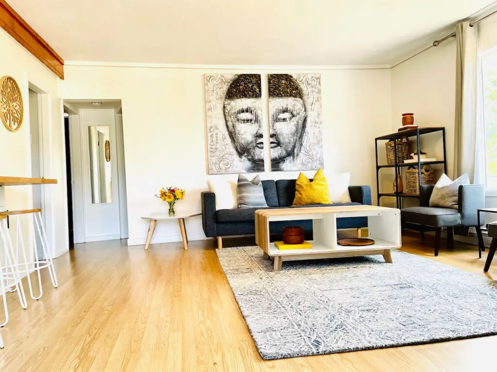 A stylish living area with a cozy sofa, modern coffee table, and decorative wall art, brightened by natural light.