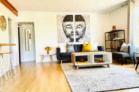 A stylish living area with a cozy sofa, modern coffee table, and decorative wall art, brightened by natural light.