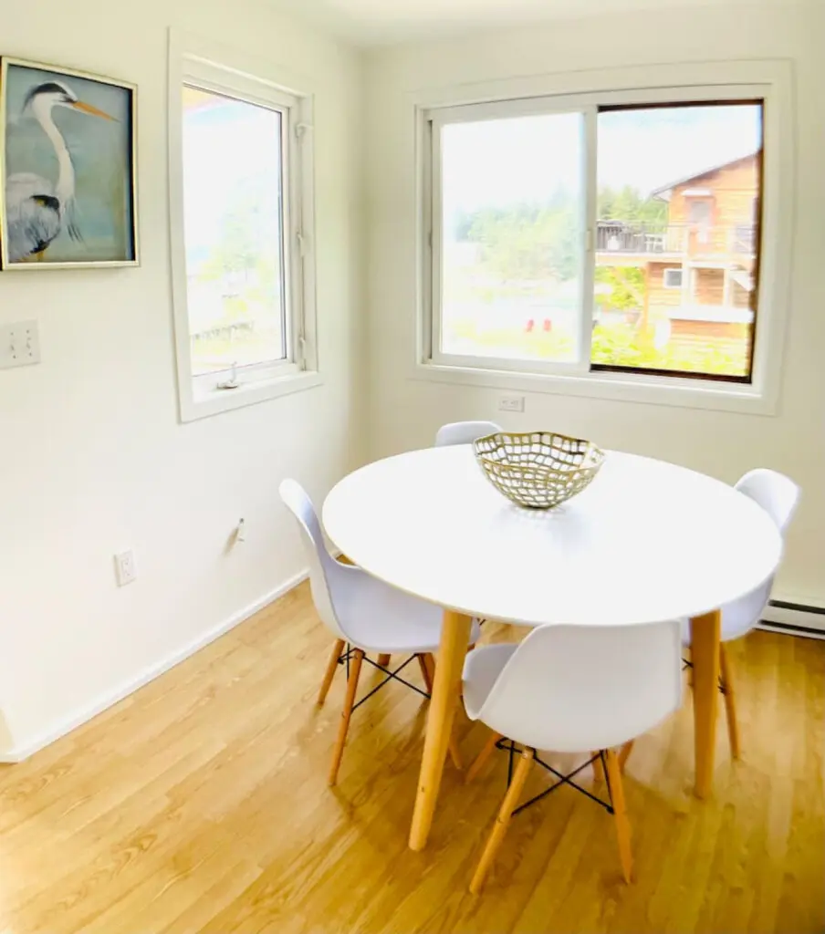 Bright dining nook with a minimalist round table, modern chairs, and large windows offering natural light and peaceful views.