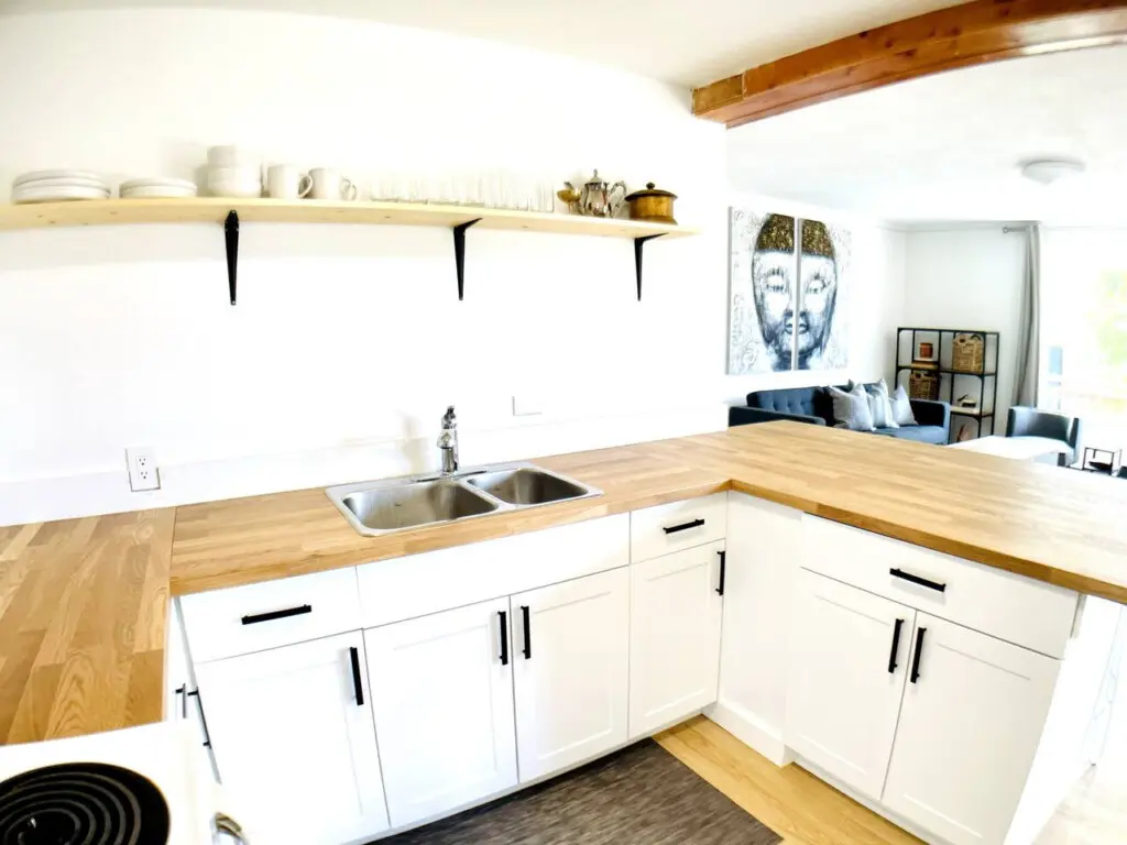 Bright and functional kitchen with modern white cabinetry, wooden countertops, and open shelving for easy access to dishes and glassware.