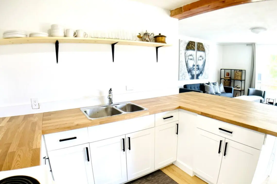 Bright and functional kitchen with modern white cabinetry, wooden countertops, and open shelving for easy access to dishes and glassware.
