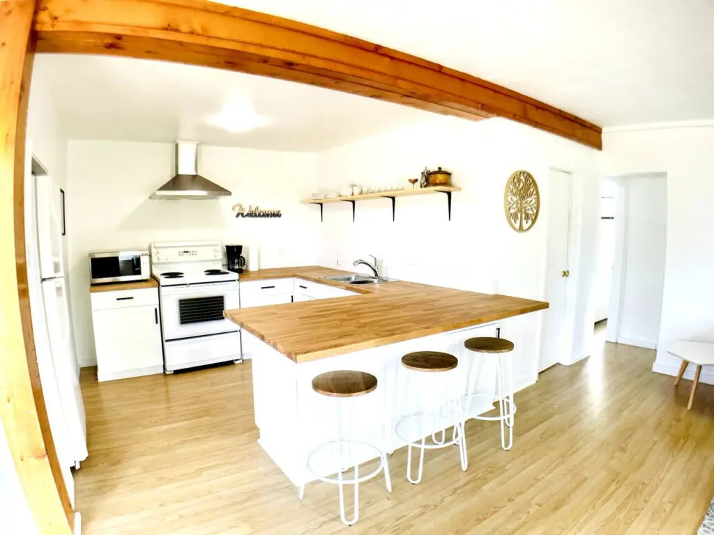 Bright, spacious kitchen featuring modern appliances, a large wooden countertop, and a cozy breakfast bar with sleek stools for casual dining.