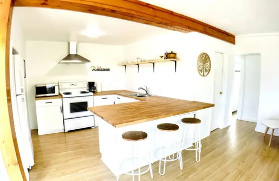 Bright, spacious kitchen featuring modern appliances, a large wooden countertop, and a cozy breakfast bar with sleek stools for casual dining.