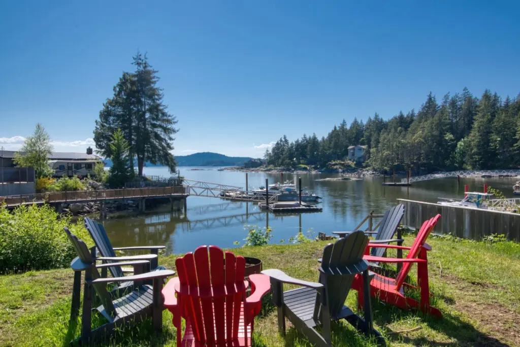Relaxing waterfront seating area with colorful Adirondack chairs overlooking a peaceful dock and scenic lake views.