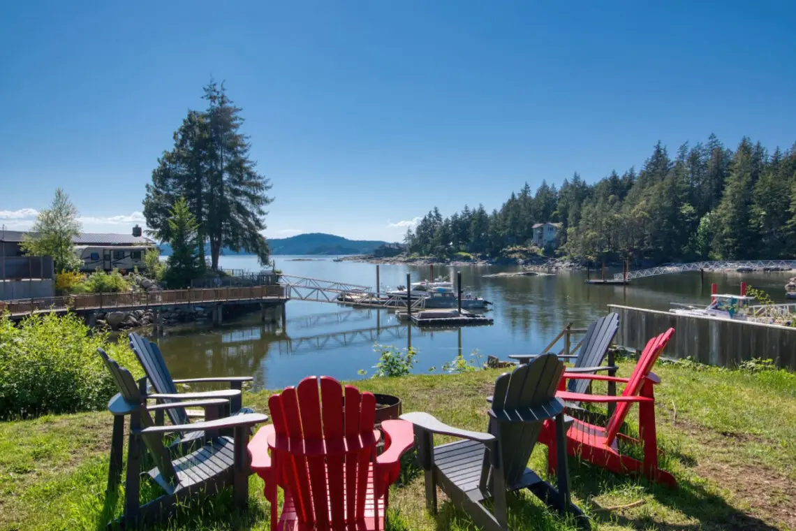 Relaxing waterfront seating area with colorful Adirondack chairs overlooking a peaceful dock and scenic lake views.