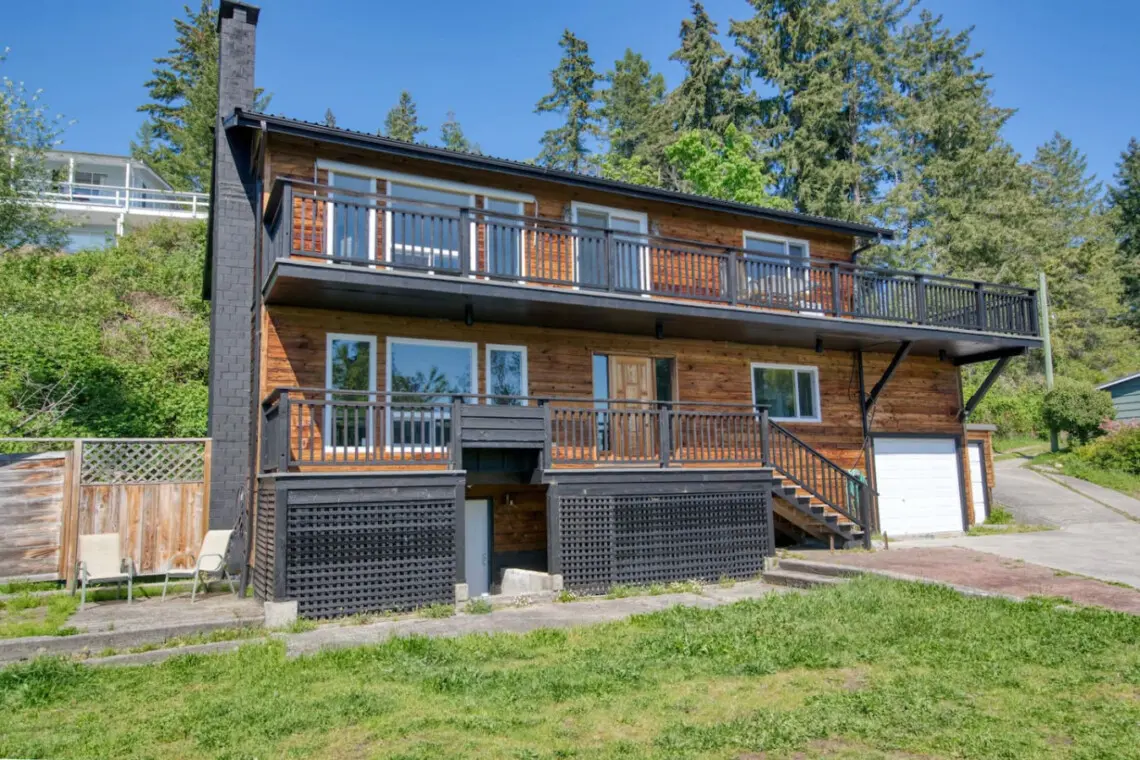 Charming multi-level wooden home with spacious balconies and large windows, offering plenty of natural light and outdoor relaxation space.
